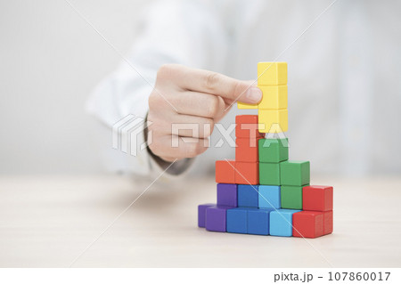 Man's hand stacking colorful wooden blocks. Business development concept Man's hand stacking colorful wooden blocks. Business development concept 107860017