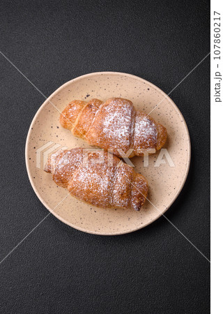 Delicious fresh sweet crispy croissants with chocolate cream on a ceramic plate Delicious fresh sweet crispy croissants with chocolate cream on a ceramic plate 107860217