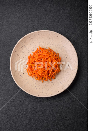 Delicious spicy carrots sliced and cooked in Korean style on a ceramic plate Delicious spicy carrots sliced and cooked in Korean style on a ceramic plate 107860300