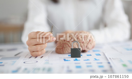 Woman hold key, lock and human brain on desk, symbol as key to someones mind Woman hold key, lock and human brain on desk, symbol as key to someones mind 107861150