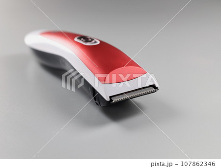 Electric trimming machine for hair, device with red colour design on grey surface Electric trimming machine for hair, device with red colour design on grey surface 107862346