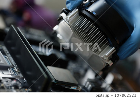 Person install cooler fan with copper tubes on computer processor, connect parts 107862523
