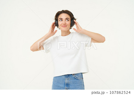 Portrait of smiling young woman, listening to music, enjoying dancing to favourite song, isolated on white background Portrait of smiling young woman, listening to music, enjoying dancing to favourite song, isolated on white background 107862524
