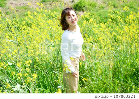 菜の花畑を散歩する女性 107863221