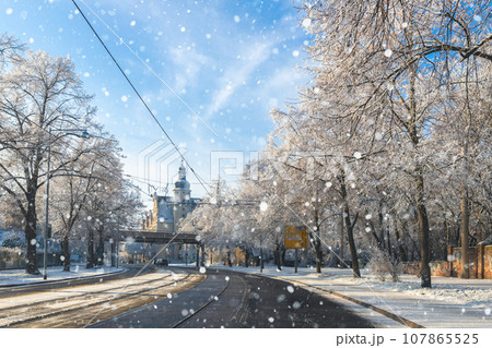Scenic view of Halberstadter street road tram rails in Magdeburg old city center against blue sky on cold frosty winter day. Snowy sunny german cityscape cold weather. European travel destination Scenic view of Halberstadter street road tram rails in Magdeburg old city center against blue sky on cold frosty winter day. Snowy sunny german cityscape cold weather. European travel destination 107865525