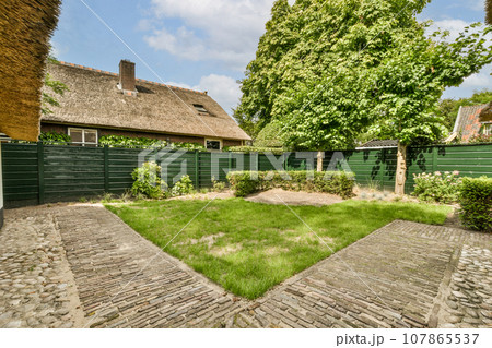 an outside area with grass, trees and brick paversed walkway leading up to a house in the background an outside area with grass, trees and brick paversed walkway leading up to a house in the background 107865537