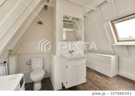 a bathroom in a small room with wood flooring and white walls, there is a mirror on the wall 107866301