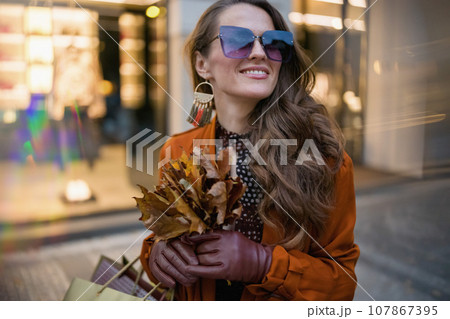 happy modern 40 years old woman in orange trench coat 107867395