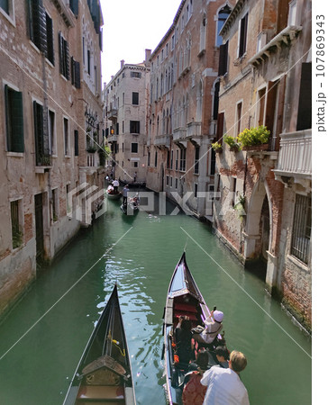 Canal with gondolas in Venice, Italy. Architecture and landmarks of Venice. Postcard with gondola. 107869343