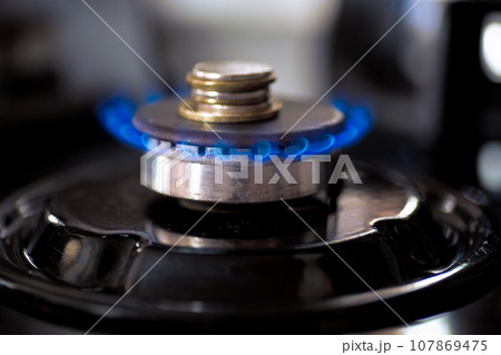 Coins accumulate on a burning gas burner. 107869475