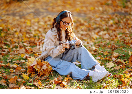 Beautiful woman taking pictures in autumn forest. Woman enjoying autumn weather. Lifestyle concept. 107869529