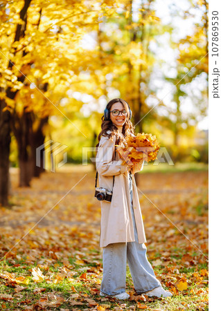 Beautiful woman taking pictures in autumn forest. Woman enjoying autumn weather. Lifestyle concept. Beautiful woman taking pictures in autumn forest. Woman enjoying autumn weather. Lifestyle concept. 107869530