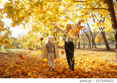 Portrait of happy mother and daughter in autumn forest at sunset. Autumn women. 107869822