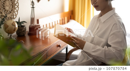 自宅の部屋で読書をするショートヘアの女性モデルのポートレイト 自宅の部屋で読書をするショートヘアの女性モデルのポートレイト 107870784