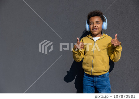 Boy in headphones dancing and looking excited 107870983