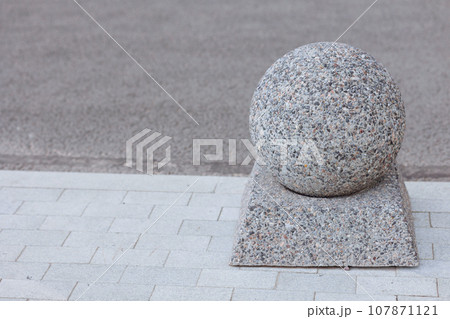 Polished granite sphere and base on sidewalk 107871121