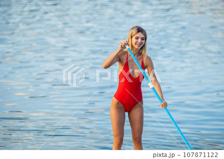 Girl with paddle on sub board floating on the water in the ocean. 107871122