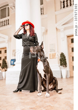 A photo of a woman and her Great Dane walking through a town, taking in the sights and sounds of the urban environment. A photo of a woman and her Great Dane walking through a town, taking in the sights and sounds of the urban environment. 107871365