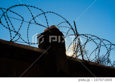 Barbed wire on the prison fence. A closed prison. Security concept. Forbidden territory. Barbed wire on the prison fence. A closed prison. Security concept. Forbidden territory. 107871600