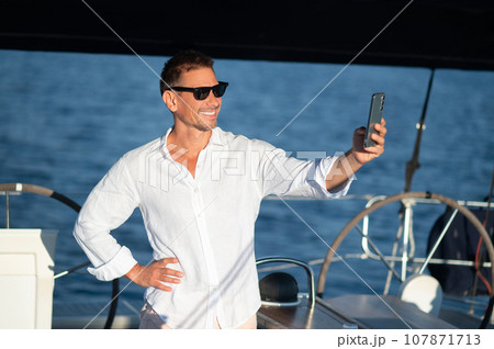 Smiling man traveling on a yacht and looking contented Smiling man traveling on a yacht and looking contented 107871713