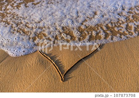 Heart shape drawn in the sand on a beach Heart shape drawn in the sand on a beach 107873708