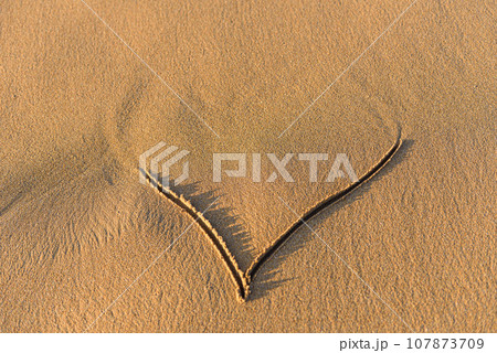 Heart shape drawn in the sand on a beach Heart shape drawn in the sand on a beach 107873709