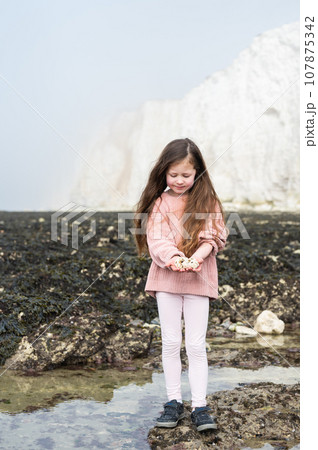 Little girl between Seaford and Eastbourne, East Sussex. Beach and sea in foggy morning Little girl between Seaford and Eastbourne, East Sussex. Beach and sea in foggy morning 107875342