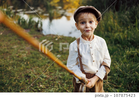 Child fishing at autumn lake 107875423