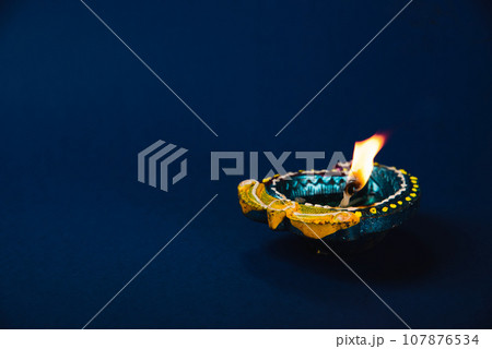 Diwali celebration with vibrant clay diya lamps on a blue background. festive invitations, radiates happiness and prosperity. Shiny glowing lamps. Diwali, Holi, lamp, and god-themed. 107876534