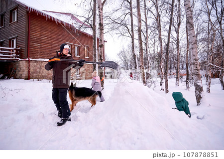 A family builds a slide in the yard in winter. 107878851