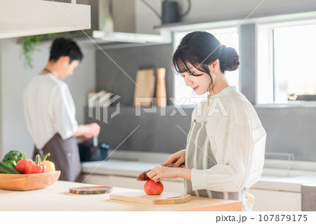 キッチンで料理・家事をする若いアジア人夫婦・カップル(包丁・切る・野菜・トマト) キッチンで料理・家事をする若いアジア人夫婦・カップル(包丁・切る・野菜・トマト) 107879175