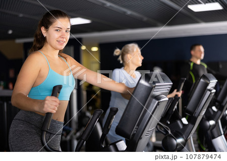 Fit young woman working out at elliptical machine in gym 107879474