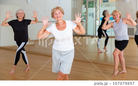 Cheerful senior woman enjoying active dancing in dance studio 107879897