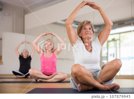 Elderly women practicing yoga trainin the lotus position 107879945