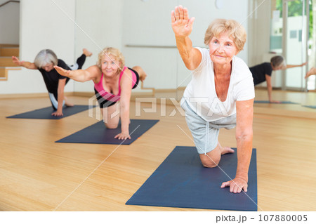 Senior woman practicing Balancing Table pose during group yoga training Senior woman practicing Balancing Table pose during group yoga training 107880005