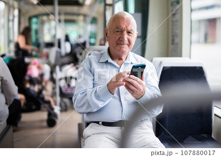 Old man with smartphone in streetcar Old man with smartphone in streetcar 107880017