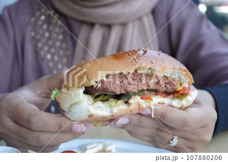 hand holding beef burger on table close up hand holding beef burger on table close up 107880206