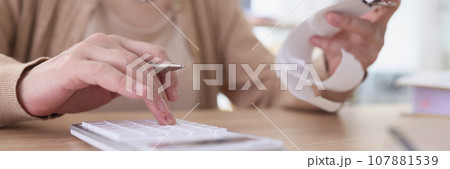 Mature woman makes counts from paper check using calculator Mature woman makes counts from paper check using calculator 107881539