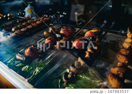 traditional caucasian shish kebab at street food market. grilled champignons, tomatos and other vegetables 107883537