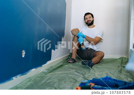 home renovation. caucasian bearded man having rest after painting wall 107883578