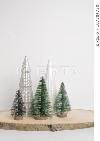 Modern Christmas trees. Decorative Beige, White and Green Christmas Decoration on a Wooden Stand with a Gray background. Nordic Festive Decor. Boho, Scandinavian Style Design Trendy Minimal Ornament. 107884730