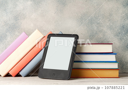Digital tablet with a stack of books on gray background 107885221
