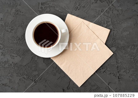 Top view of coffee cup and paper napkins on gray background Top view of coffee cup and paper napkins on gray background 107885229