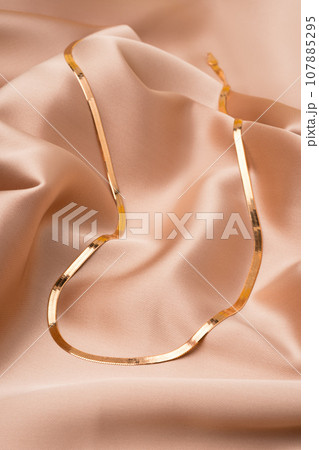 Golden chain necklace on beige silk background Golden chain necklace on beige silk background 107885295