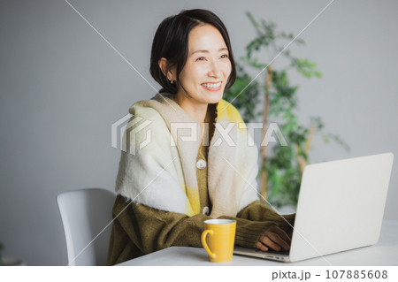 コーヒーを飲みながらパソコンを見る女性 107885608