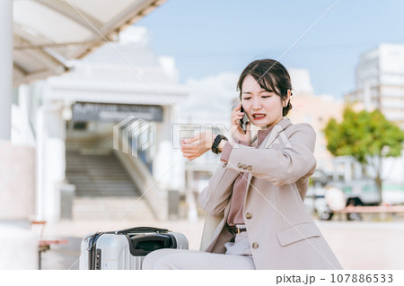 腕時計を確認しながらスマホで電話するビジネスウーマン・若い女性 107886533
