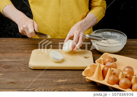 Unrecognizable man cut onion bulb on half Unrecognizable man cut onion bulb on half 107886936