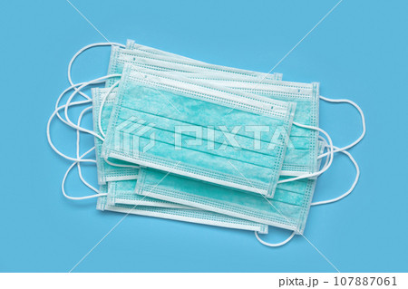 Surgical face mask on blue background protection against COVID-19 coronavirus. Healthcare and medical concept 107887061