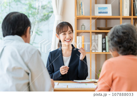 シニアの夫婦に説明するビジネスウーマン シニアの夫婦に説明するビジネスウーマン 107888033