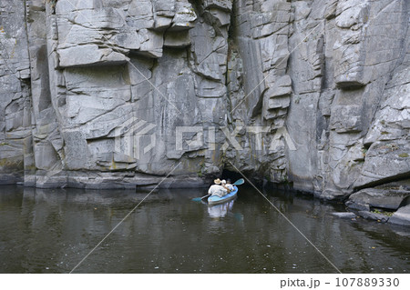 Canoe with people aboard going inside of a cave of rocks. Buksky canyon, Ukraine 107889330